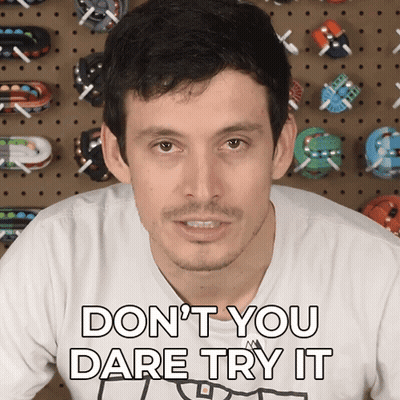 A Man Says " Don T You Dare Try It " In Front Of A Wall Of Toy Cars GIF