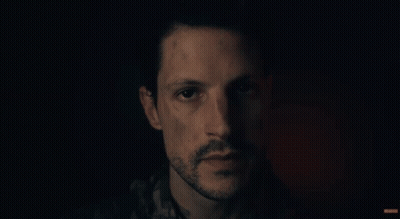 A Man Says " Glad You Made It Here Safely " In A Dark Room GIF