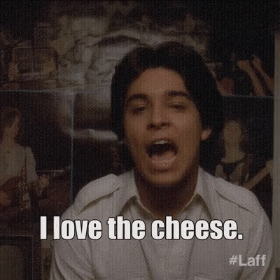 A Man Says I Love The Cheese In Front Of A Wall Of Pictures GIF