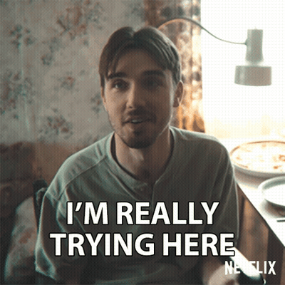 A Man Says I 'M Really Trying Here While Sitting At A Table GIF