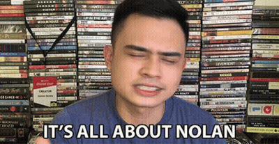 A Man Says It 'S All About Nolan In Front Of A Stack Of Books GIF