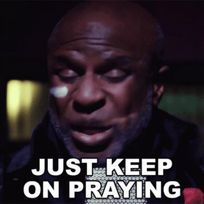 A Man Says " Just Keep On Praying " In Front Of A Dark Background GIF