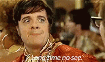 A Man Says Long Time No See While Looking At Another Man . GIF