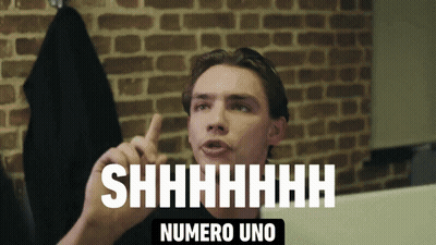 A Man Says Shhhh Numero Uno In Front Of A Brick Background GIF