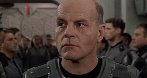 A Man Says Welcome To The Roughnecks In Front Of A Group Of People GIF
