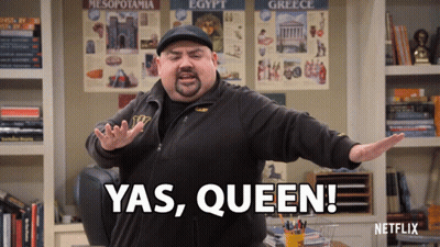 A Man Says Yas Queen In Front Of A Shelf Full Of Books GIF