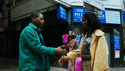 A Man Shakes Hands With Another Man In Front Of A Nhs Sign GIF
