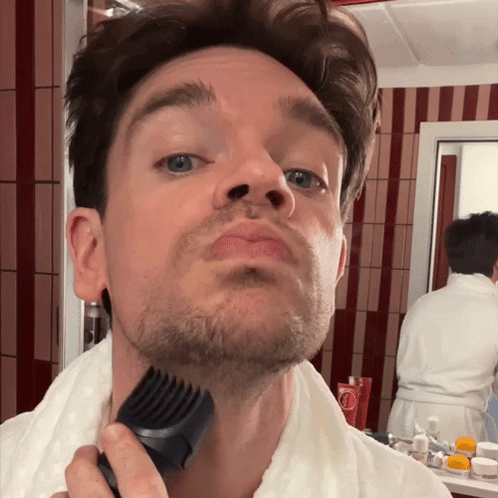 A Man Shaves His Beard With A Comb In Front Of A Mirror GIF