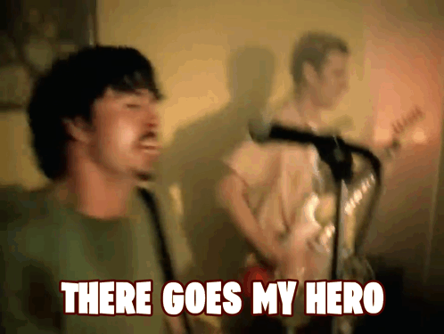 A Man Singing In Front Of A Microphone With The Words " There Goes My Hero " Below Him GIF