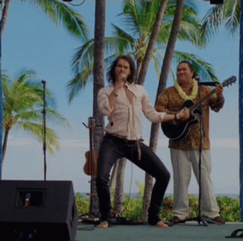 A Man Singing Into A Microphone And Another Man Playing A Guitar GIF