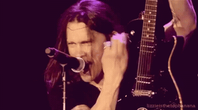 A Man Singing Into A Microphone And Holding A Guitar GIF