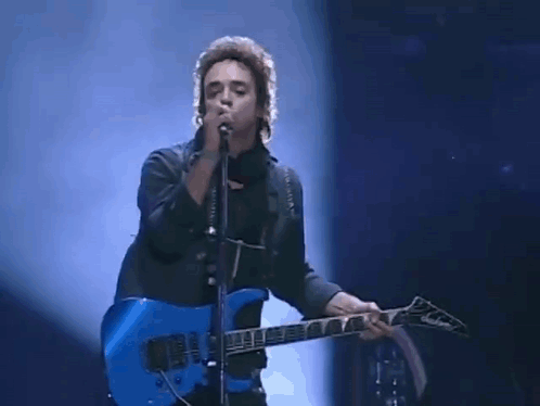 A Man Singing Into A Microphone And Playing A Blue Guitar GIF