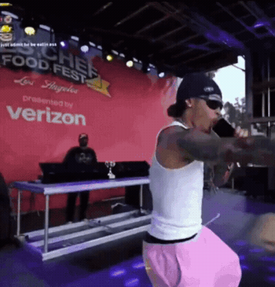 A Man Singing Into A Microphone At A Food Fest GIF