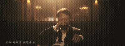 A Man Singing Into A Microphone In A Dark Room With Chinese Writing On The Bottom GIF