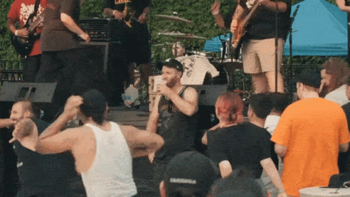 A Man Singing Into A Microphone In Front Of A Crowd Wearing A Cap That Says ' Chicago ' On It GIF