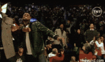 A Man Singing Into A Microphone In Front Of A Crowd With A Tnt Logo In The Corner GIF