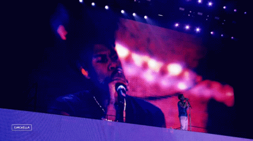 A Man Singing Into A Microphone In Front Of A Screen That Says Cancel GIF