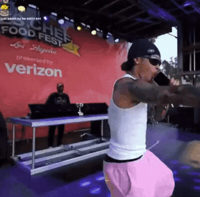A Man Singing Into A Microphone In Front Of A Sign That Says Chef Food Fest GIF
