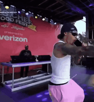 A Man Singing Into A Microphone In Front Of A Sign That Says Chef Food Fest GIF