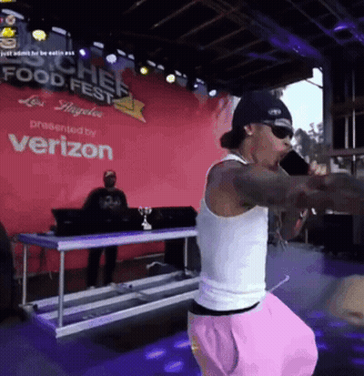 A Man Singing Into A Microphone In Front Of A Verizon Sign GIF