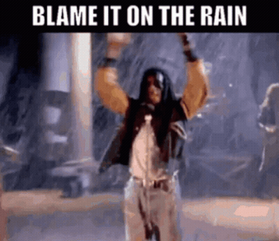 A Man Singing Into A Microphone In The Rain With The Words Blame It On The Rain Below Him . GIF