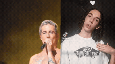 A Man Singing Into A Microphone Next To Another Man Wearing A White Vans Shirt GIF