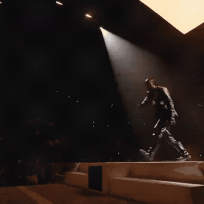 A Man Singing Into A Microphone On A Stage GIF