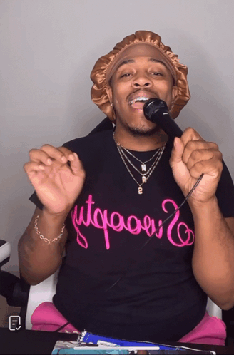 A Man Singing Into A Microphone Wearing A T-Shirt That Says " Utqaoui " GIF