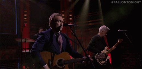 A Man Singing Into A Microphone While Another Man Plays A Guitar On A Stage With The Hashtag #Fallontonight GIF