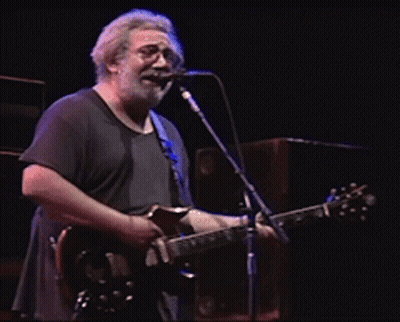 A Man Singing Into A Microphone While Holding A Guitar GIF