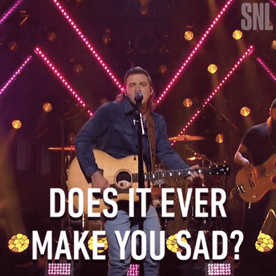 A Man Singing Into A Microphone While Holding A Guitar With The Words " Does It Ever Make You Sad " Above Him GIF