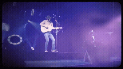 A Man Singing Into A Microphone While Playing A Guitar GIF