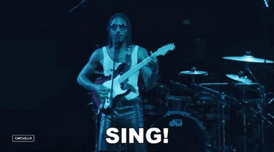 A Man Singing Into A Microphone While Playing A Guitar In Front Of A Dw Drum Set GIF