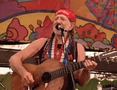 A Man Singing Into A Microphone While Playing A Guitar . GIF