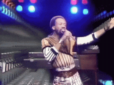 A Man Singing Into A Microphone While Playing A Keyboard GIF