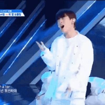 A Man Singing Into A Microphone While Wearing A White Shirt GIF