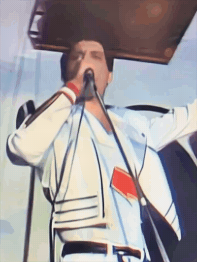 A Man Singing Into A Microphone While Wearing A White Shirt GIF