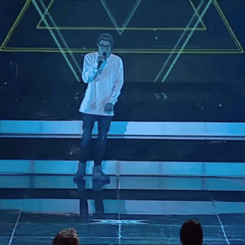 A Man Singing Into A Microphone While Wearing Glasses And A Hat GIF