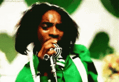 A Man Singing Into A Microphone With A Green Jacket On GIF