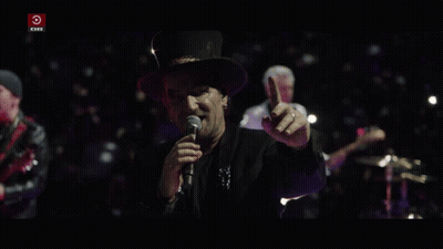 A Man Singing Into A Microphone With A Red Circle That Says Dr On It GIF