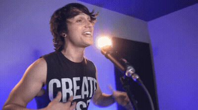 A Man Singing Into A Microphone With A Shirt That Says Create GIF