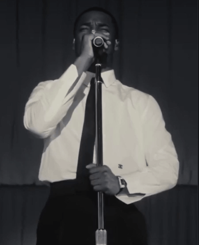 A Man Singing Into A Microphone With A Watch On His Wrist GIF