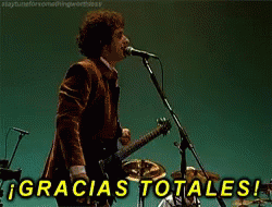 A Man Singing Into A Microphone With Gracias Totales Written In Yellow GIF