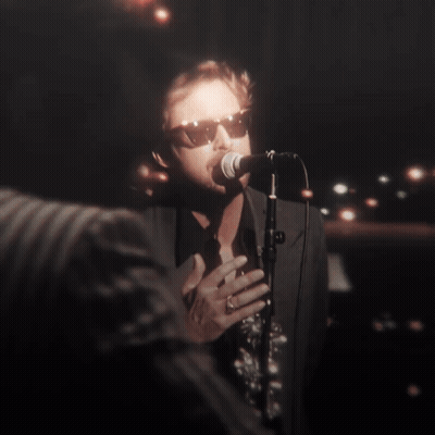A Man Singing Into A Microphone With His Eyes Closed GIF