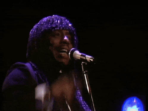 A Man Singing Into A Microphone With His Fist Up GIF