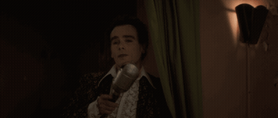 A Man Singing Into A Microphone With His Mouth Open GIF