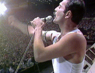 A Man Singing Into A Microphone With His Mouth Open GIF