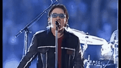 A Man Singing Into A Microphone With Sunglasses On GIF