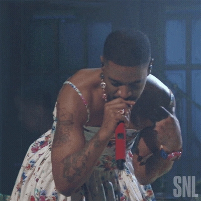 A Man Singing Into A Microphone With The Snl Logo In The Corner GIF