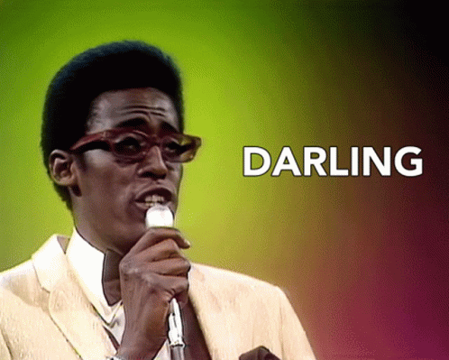 A Man Singing Into A Microphone With The Words Darling Behind Him GIF